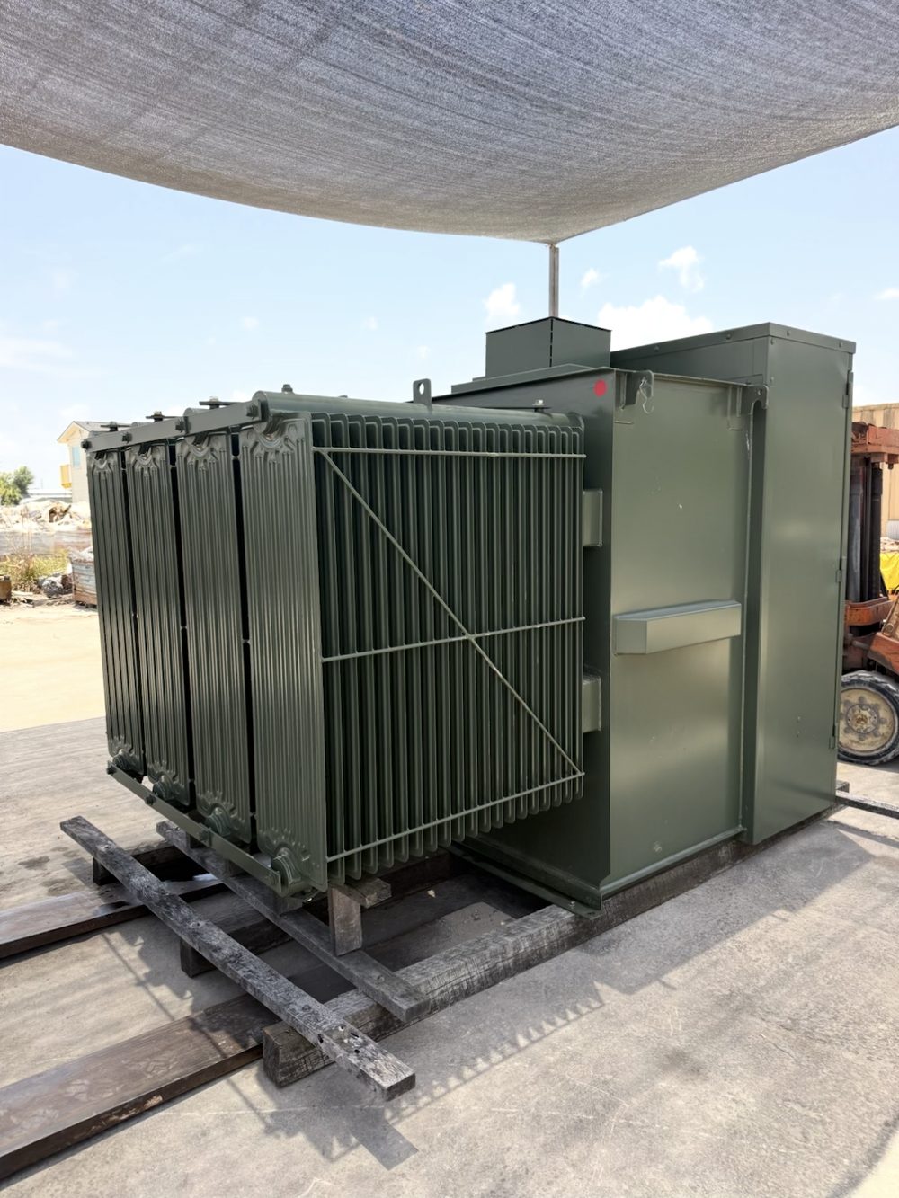 Large oil-filled substation transformer with radiator fin banks, loaded on rails and skids ready for transport